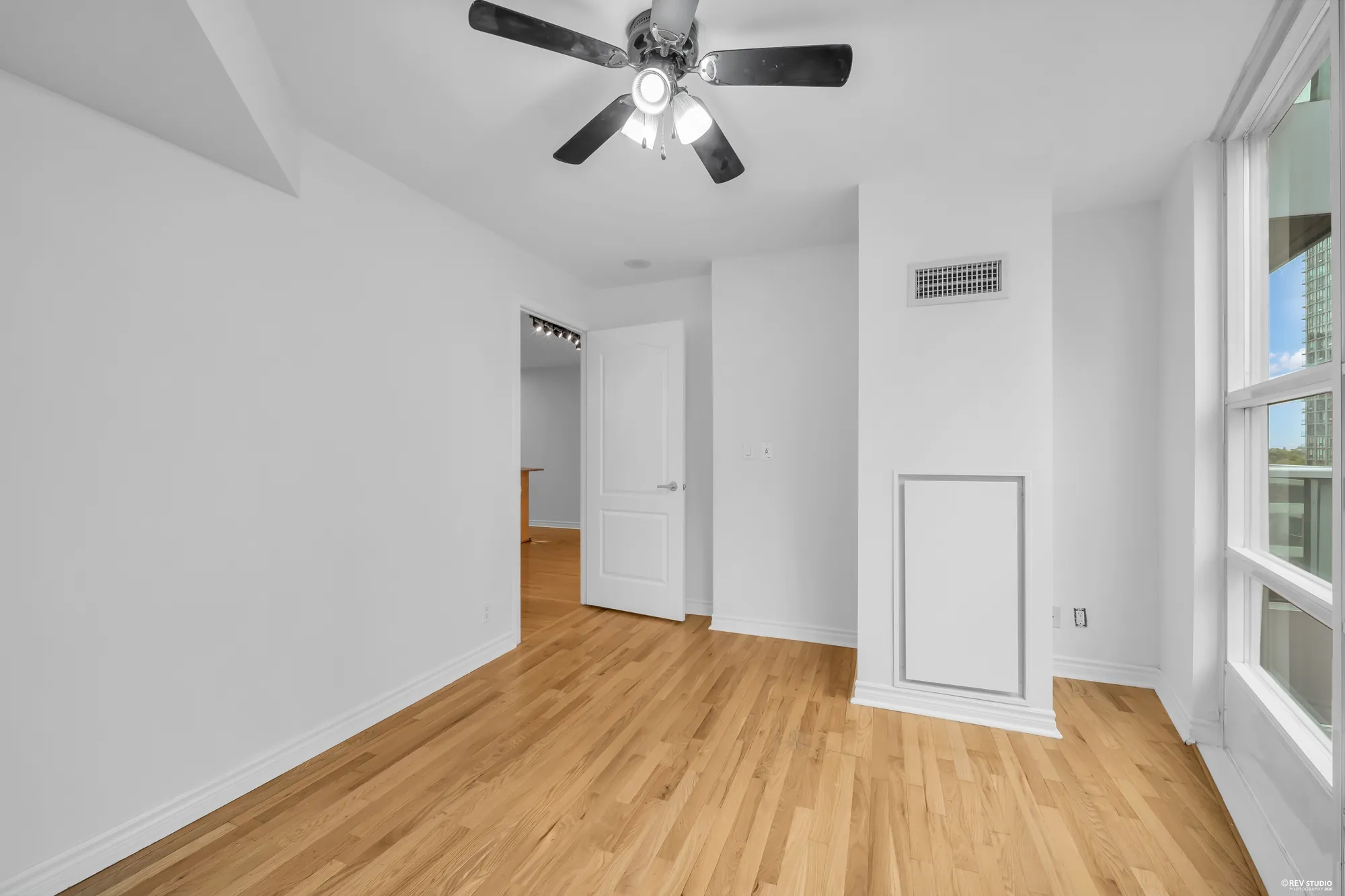 The bedroom toward its door and the hall, the ceiling fan above