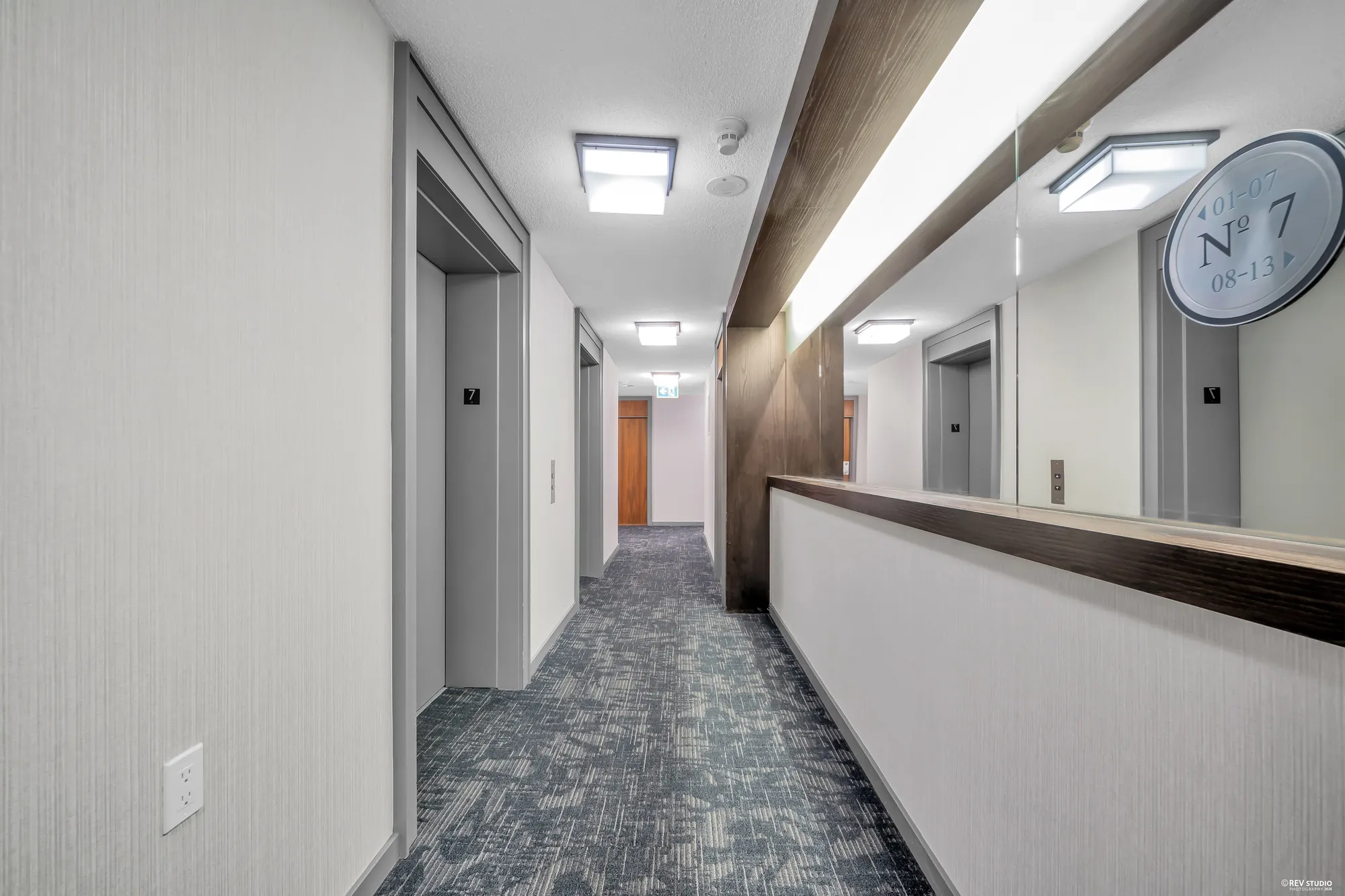 The seventh-floor corridor: patterned carpet, wood-panelled walls, a clock, the elevators