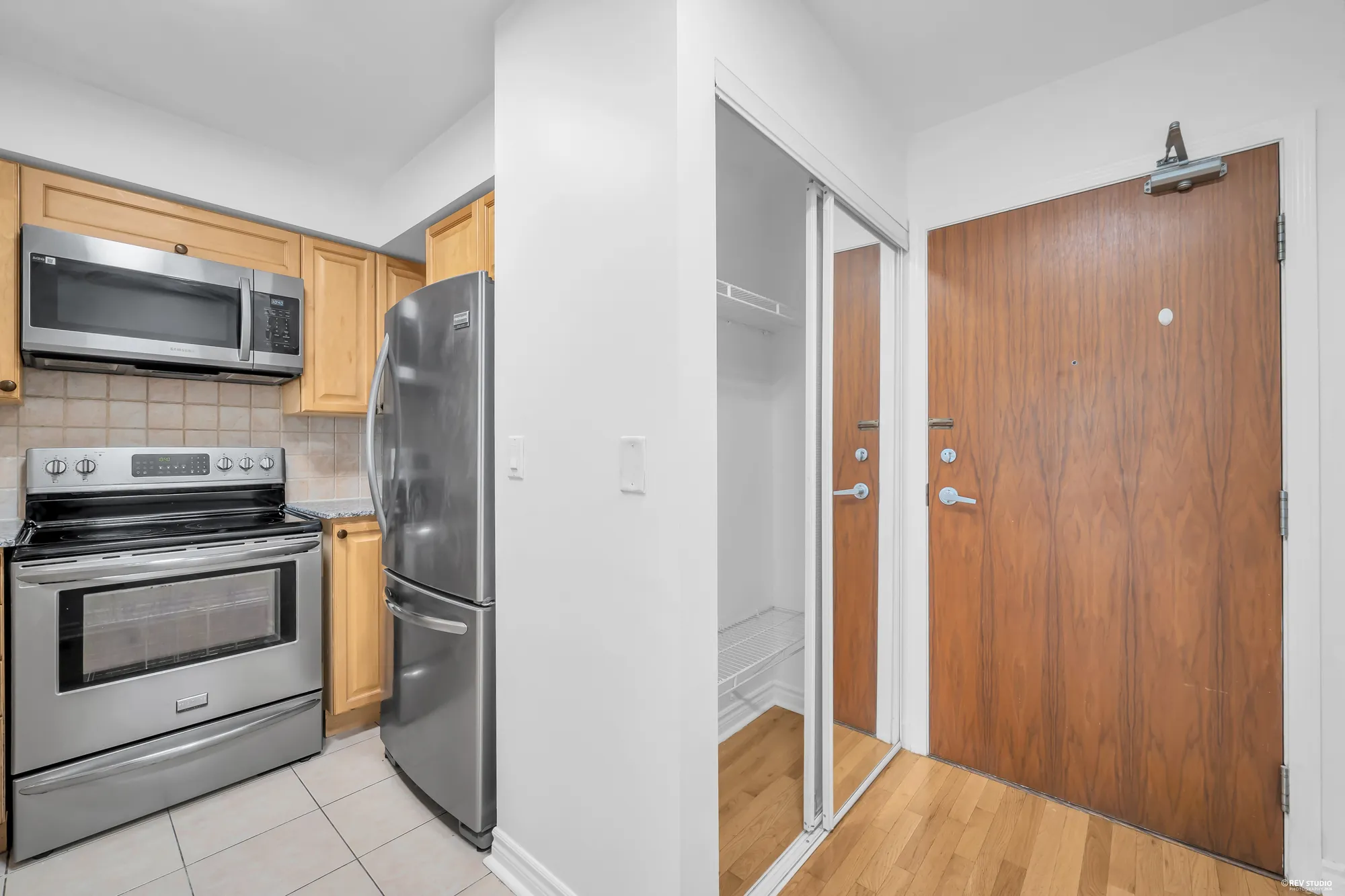 The kitchen from the front door: the range and refrigerator, the mirrored closet, the wood door