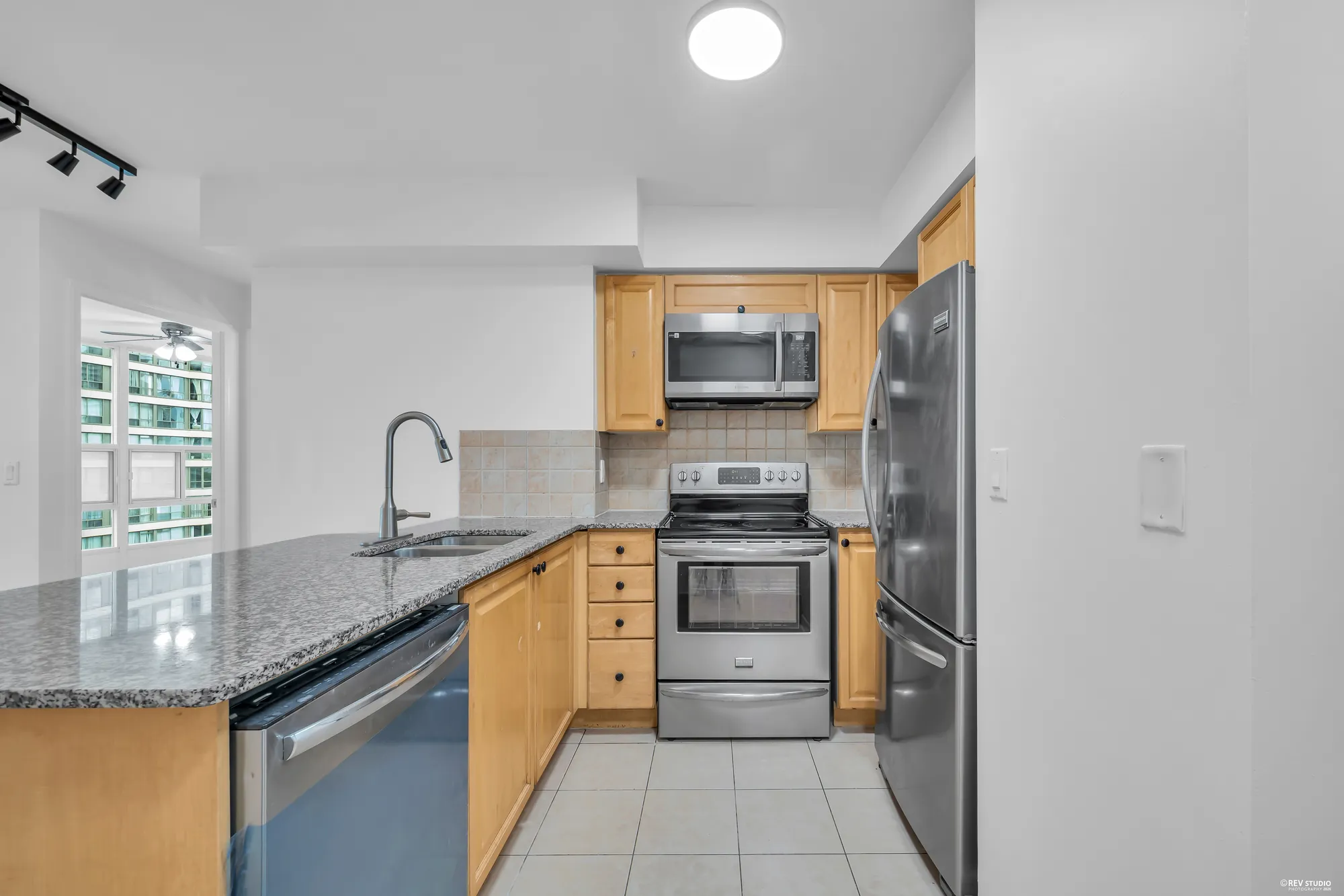 The kitchen's sink and dishwasher in the peninsula, the range and microwave, the tile floor