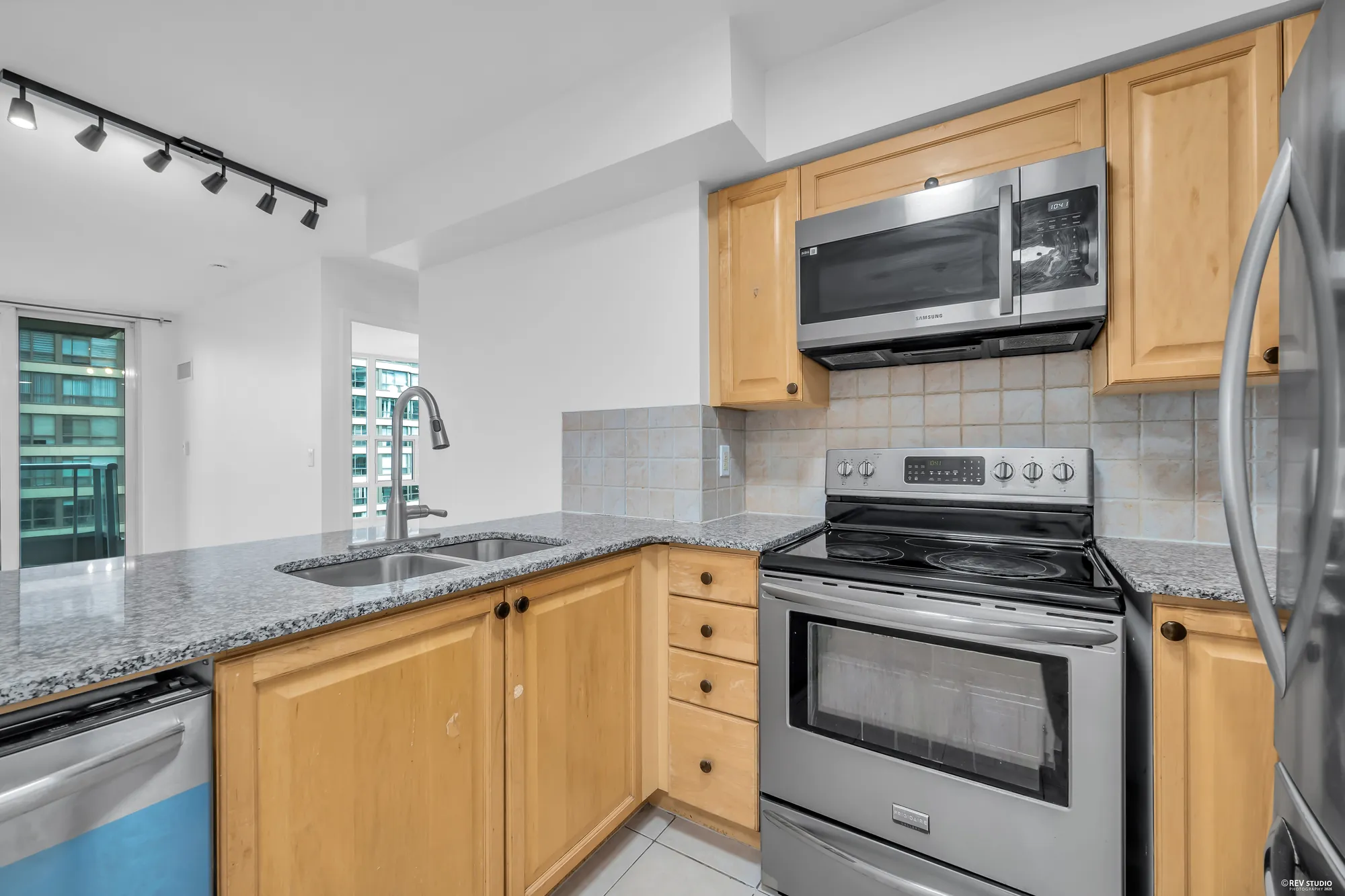 The range wall: stainless range, microwave, maple uppers, the tile backsplash