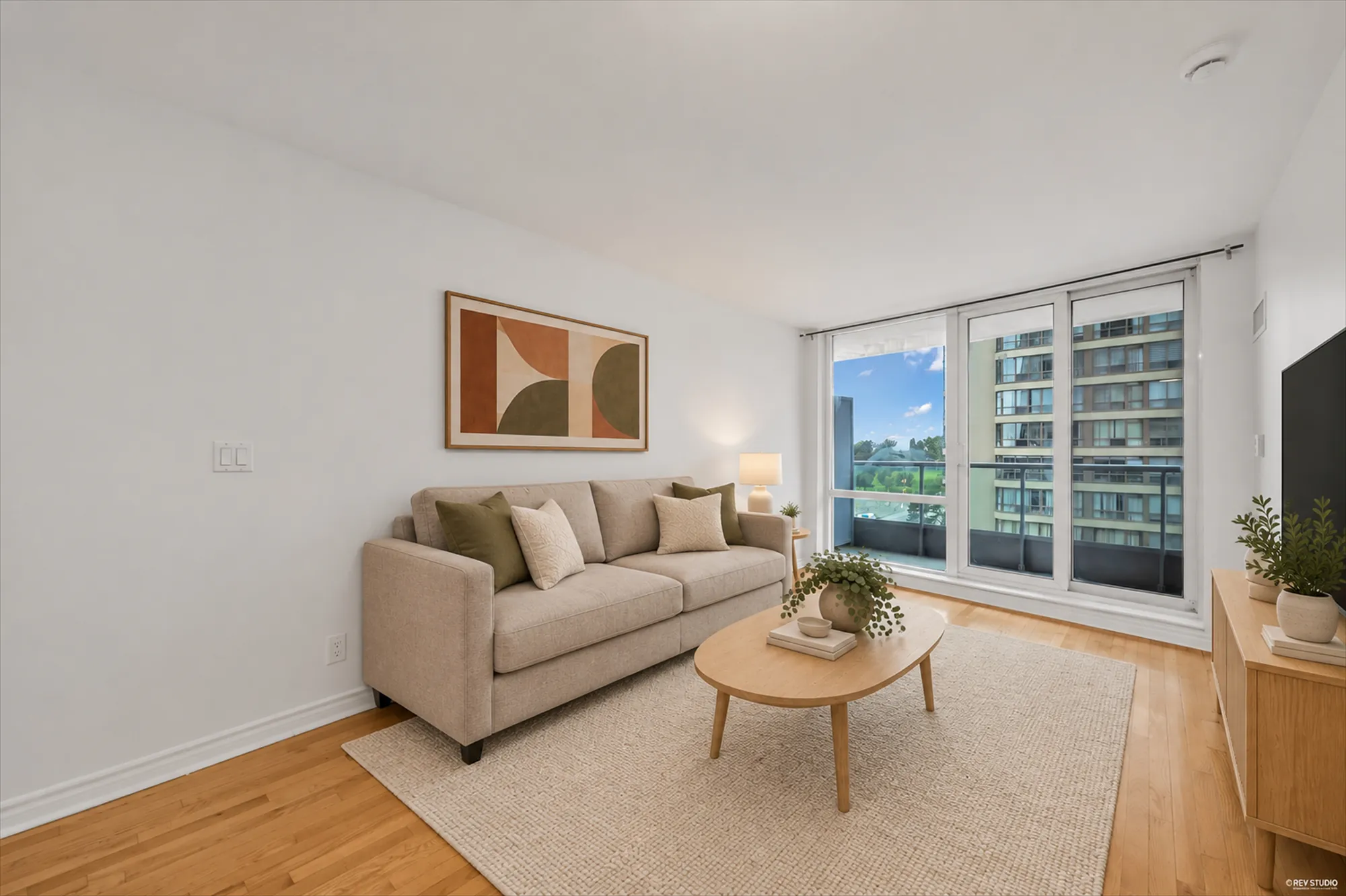 The same view virtually staged: a beige sofa, a rug, a coffee table, a picture and a lamp added