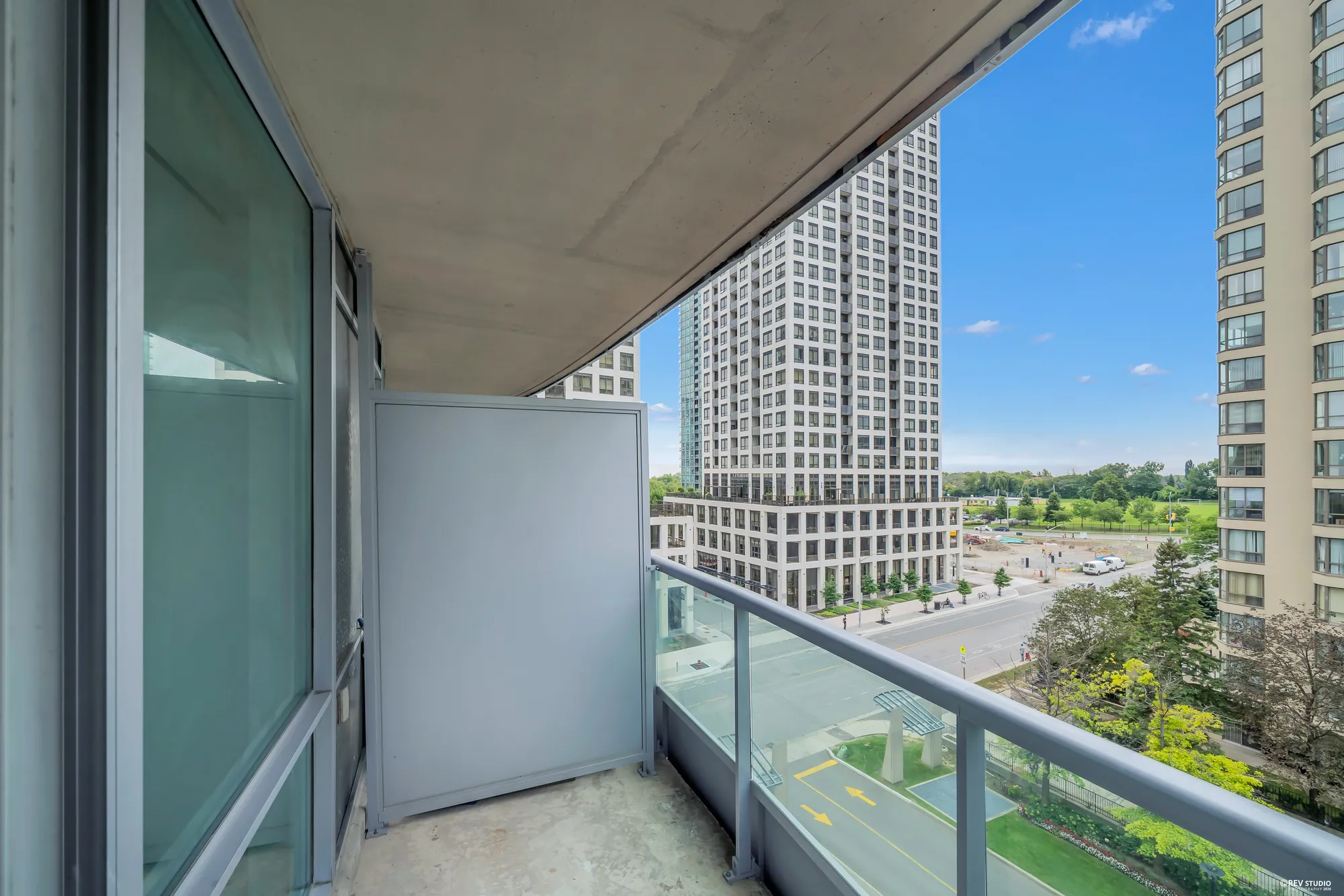 The balcony: a concrete floor, a glass railing, the tower next door and the parkland beyond